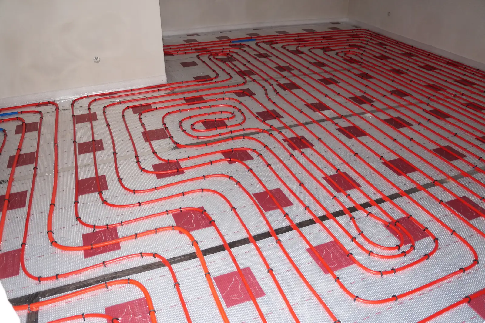 Red radiant heating tubing laid in loops across a floor